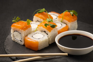 Portion of Japanese sushi Philadelphia on a stone plate on a black background © Anastasiya
