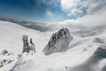 Beautiful view of snow covered mountain rocks sunlit and blown by the wind.