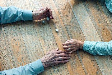 high angle view of elderly female and male hands playing dice rolling