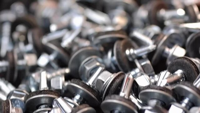 Roofing screws are lying on the table close-up. Smooth passage of the slider over the screws.