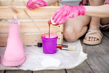 Obraz na płótnie Canvas Young woman painting wooden box in pink color, doing housework on terrace, close-up view. DIY concept