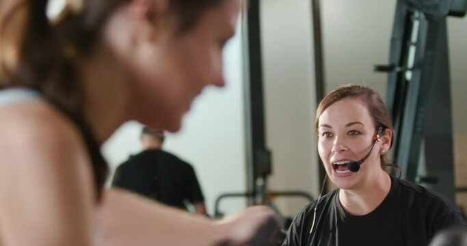 Passionate fitness coach pushes athletes to finish an intense interval workout on spin bikes