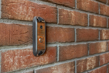An intercom with a call button made of metal mounted on a brick wall
