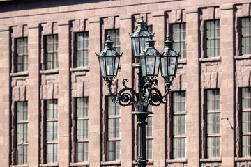 Historic lamppost with four lanterns against the background of a brown historic building in the city of St. Petersburg, Russia
