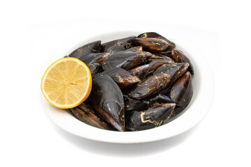 Raw mussels in a white bowl, with half a lemon, isolated on white background. It feeds on phytoplankton and zooplankton, and even decomposing organic particles found in seawater.