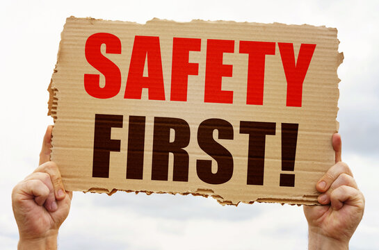 In the hands of a man is a cardboard sign with the inscription - Safety first