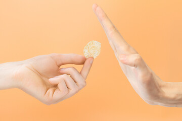 Fototapeta na wymiar Man's hand refusing a rice chip on an orange background. Natural. Salty. White. Nourishment. Flavoured. Snack. Expression. Crispy. Holds. Delicious. Refreshing. Spice