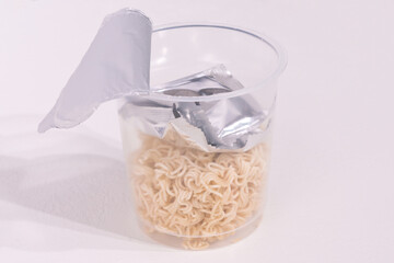 Open a transparent noodle cup with a package of seasoning inside on a white background. Instant noodles, Asian fast food. Content. Flavour. Delicious. Fastfood. Ready. Fast. Cuisine. Food. Instant