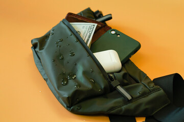 Water drops on a waterproof waist bag on an orange background.  Items. Things. Strap. Style....