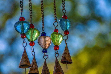 Colourful bells and glass beads on a wind chime, outdoors, sunny, nobody