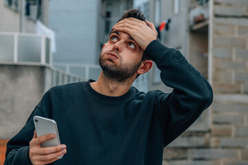 young man with mobile phone and expression of stress