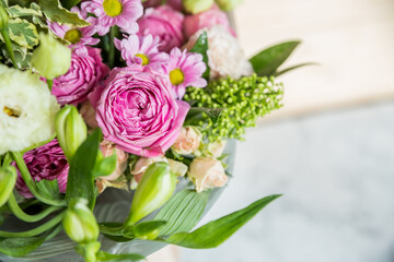 big bouquet of roses, daisies, lisianthus, chrysanthemums, unopened buds on a white table. bouquet for Woman's Day, mother's day or Valentine's Day.