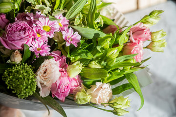 big bouquet of roses, daisies, lisianthus, chrysanthemums, unopened buds on a white table. bouquet for Woman's Day, mother's day or Valentine's Day.