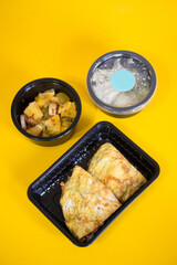 Omelet and fruit salad in container on yellow background