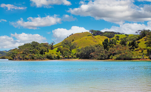 Beautiful dreamlike scenic coastal landscape with seascape, lush green hills, blue sky with fluffy cumulus clouds - Pataua, New Zealand, North Island