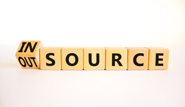 Outsource or insource symbol. Turned a wooden cube and changed the concept word Outsource to Insource. Beautiful white table white background, copy space. Business outsource or insource concept.