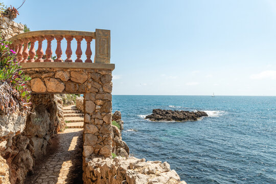 Paysage en bord de mer sur le Cap d'Antibes avec un passage sous une terrasse  avec une balustre en pierre