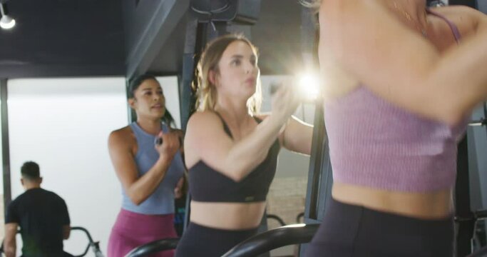 Trio of athletic women workout out on climbing machines at a cross training gym