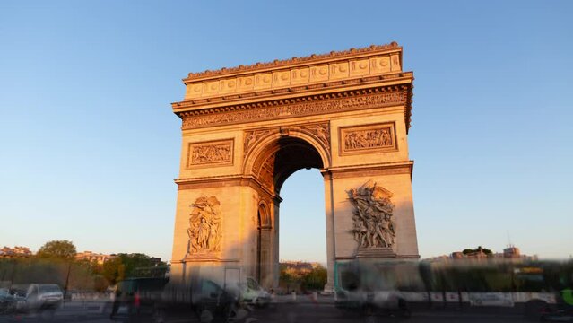 Paris France: Triumphal Arch of the Star (Arc de Triomphe de l'&Eacute;toile) - famous landmark and tourist attraction at sunrise. Traffic on the street in a sunny morning under clear blue sky.