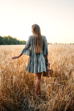 Cottagecore, simple living, slow life, country aesthetic lifestyle, modern rural fantasy, pastoral aesthetic. Young girl in peasant dress with straw handbag enjoying nature on sunset