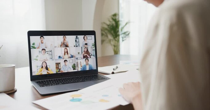 Young asia female listen leader on video call with diverse multiracial colleagues on online with laptop in kitchen at house. Girl student distance learn online at house, Online meeting concept.