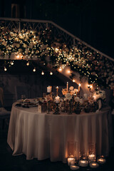 candles and lights of garlands at night on the festive table