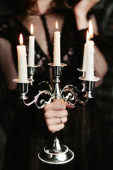 Candelabra with burning candles in the girl's hand.