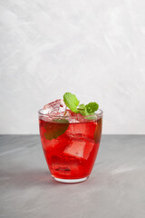 Iced fruit red cocktail or cold watermelon drink with hibiscus and mint leaf. Refreshing summer drink. Grey background, copy space