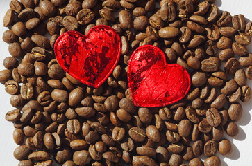Two red hearts on a background of fresh coffee beans. Fresh coffee beans background, top view....
