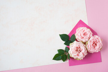Background for congratulation, pink roses in an envelope and paper for text. Greeting card for Valentine's Day, Mother's Day and other holidays