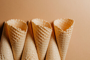 Waffle ice cream cones on a brown background top view. Sweet waffles and close-up texture.