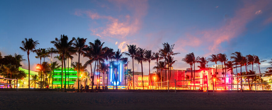 Miami Beach Ocean Drive panorama with hotels and restaurants at sunset. City skyline with palm trees at night. Art deco nightlife on South beach