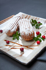 Cream eclairs choux pastries served with fresh cranberries on a handmade ceramic plate. Profiterole cupcakes - 501634022