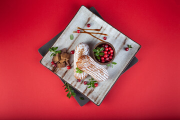 Cream eclairs choux pastries served with fresh cranberries on a handmade ceramic plate. Profiterole cupcakes - 501634023