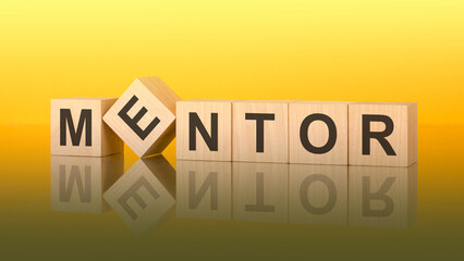 mentor word is made of wooden blocks lying on the yellow table, concept