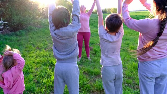 big family, mother and children do exercises together in rays of the setting sun, concept of energy every day routine practice good man health mindfulness for strength and endurance, outdoor sports