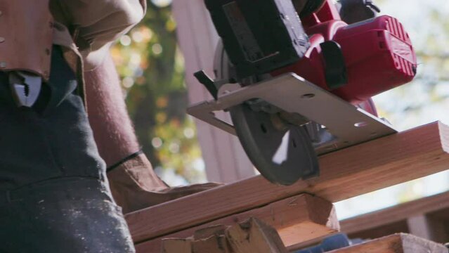 Craftsman cuts wood with a saw on a home building site