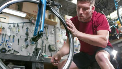 A mechanic spins the wheel on a bicycle in a cycle shop