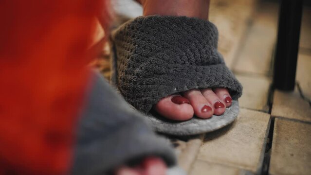 The girl wears slippers on her feet and moves her fingers with nail polish. Close-up shooting
