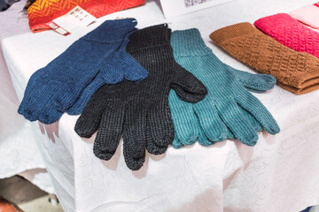 multicolored women's gloves knitted by hand with alpaca fiber with ancestral designs and geometric figures of striking colors placed on a table with a white tablecloth illuminated with natural light