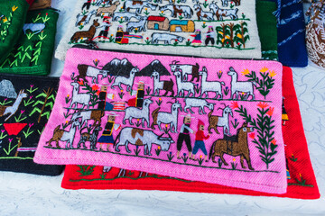 colored bags embroidered and woven on alpaca fiber looms with ancestral designs and geometric figures in bright colors laid out on a table with a white tablecloth