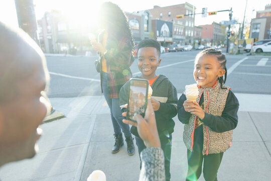 Father Photographing Kids With Ice Cream Cones On Sunny Sidewalk