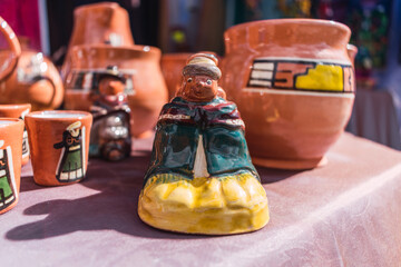 indigenous woman with typical ceramic costume handmade with geometric figures ancestral engravings illuminated with natural light placed on a table in a market stall in the Andes