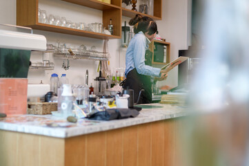 Young service minded barista woman working in coffee shop