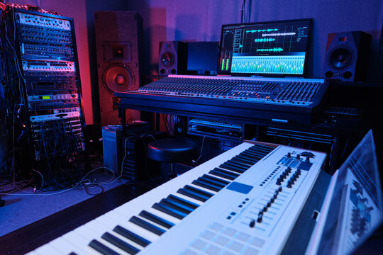 Horizontal No People Shot Of Recording Studio Room Interior With Mixing Console, Digital Piano, Loudspeakers And Other Equipment In Neon Light