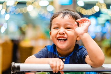toddler boy child sitting on shopping cart during family shopping on grocery store hypermarket.Kid boy smile with milk teeth happy emotion and buying food and skin care baby toddler product grocery.