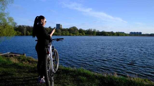 a bicycle with a woman in the sunset overlooking the lake, river. Making photos on smartphone