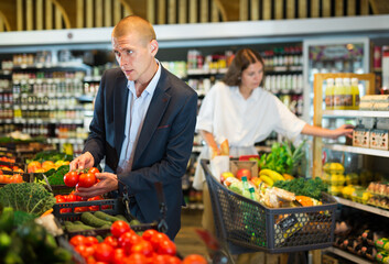 Young man looking for fresh organic vegetables at supermarket