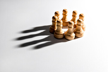 chess pawns on white background with crown-shaped shadow, game of chess.