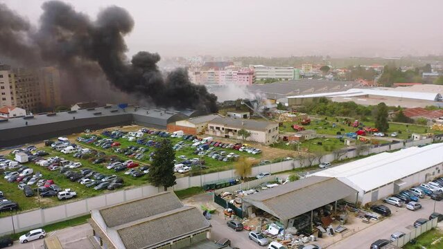 Aerial view around firetrucks at a raging building fire in a city - circling, drone
